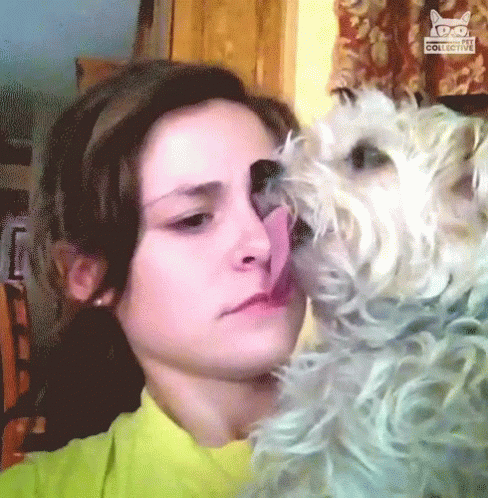 woman kisses her dog as the light streams through