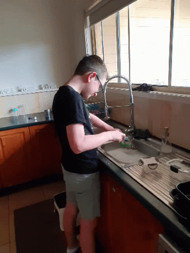 a man standing in a kitchen washing dishes on a sink