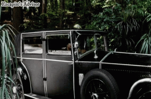 an old fashion car in a forest with a man behind the steering