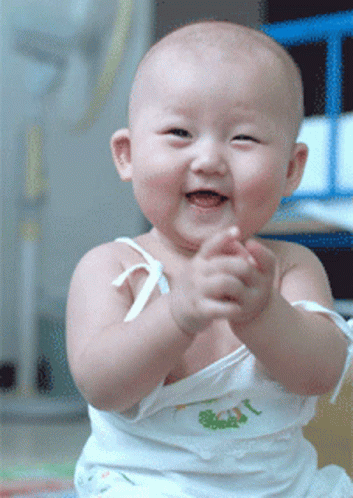 a baby in a white tank top is playing with soing