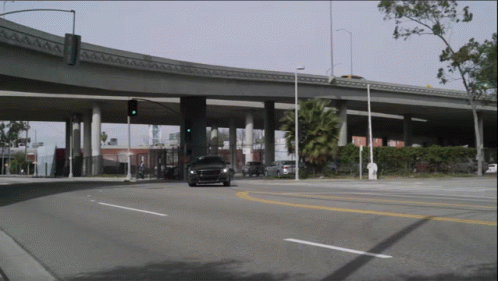 a vehicle driving under an overpass in the middle of a town