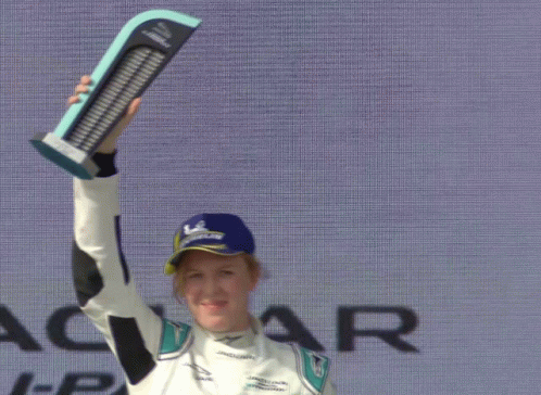 a race car driver holds his trophy on the podium
