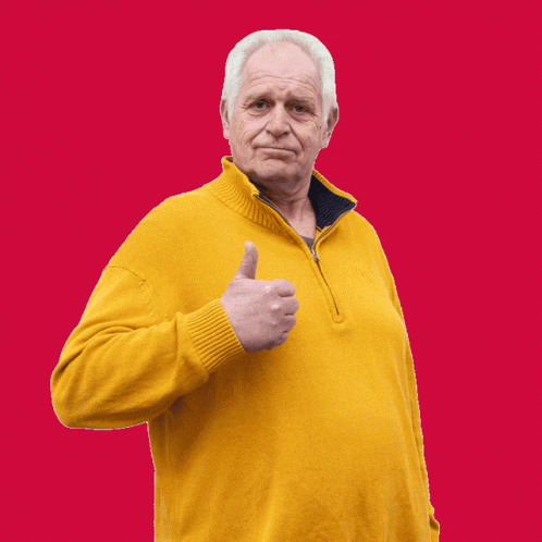an older man with a sweater giving a thumbs up