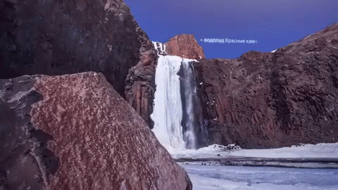 a waterfall is in the middle of a rocky landscape