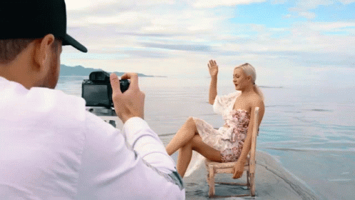 a man taking a picture of a woman sitting in a chair