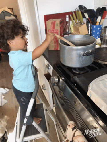 a child on a stool in front of a stove