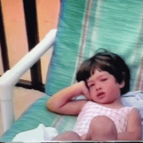 little girl covered up in purple while sitting on a porch chair