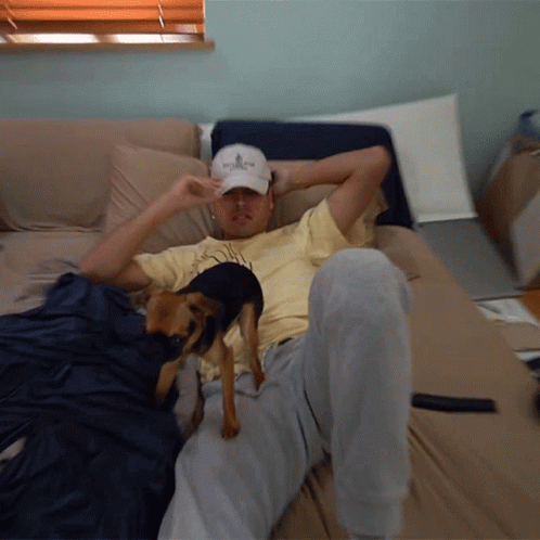 a man sleeping on a couch with a dog in his lap