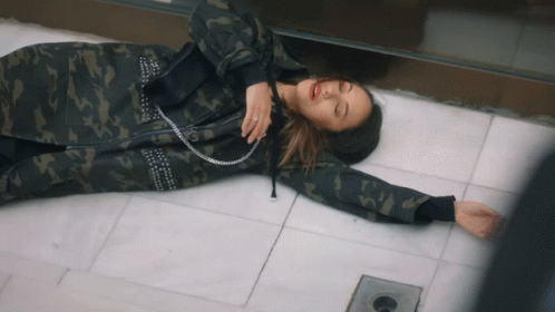 a woman dressed in camouflage lying on a floor