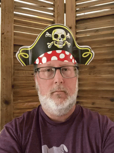 a man with glasses is wearing a pirate hat