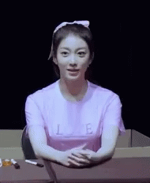 an asian girl in pink shirt standing next to a laptop