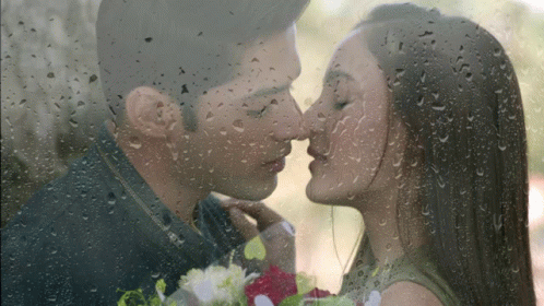 an image of a couple kissing behind a rain soaked window