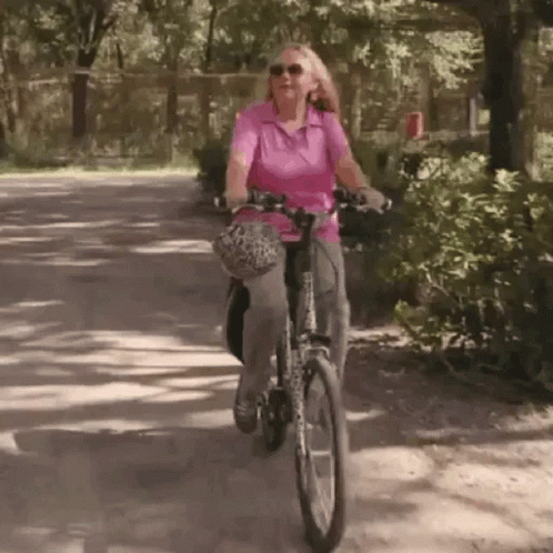 an older woman riding a bike down the street