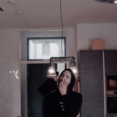 woman talking on a phone in the kitchen while holding up her arm