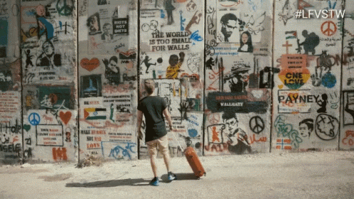 a person standing in front of a wall covered with graffiti