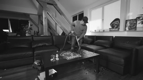 a person vacuuming a living room with black furniture