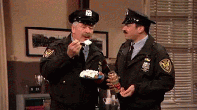 two police officers in uniforms are eating cake
