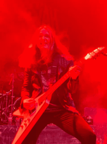 a man with long hair holding onto an electric guitar