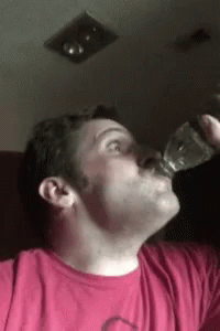 a man that is standing up drinking from a bottle
