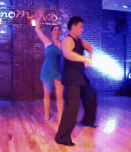 two people in dark clothes dance on wooden floor