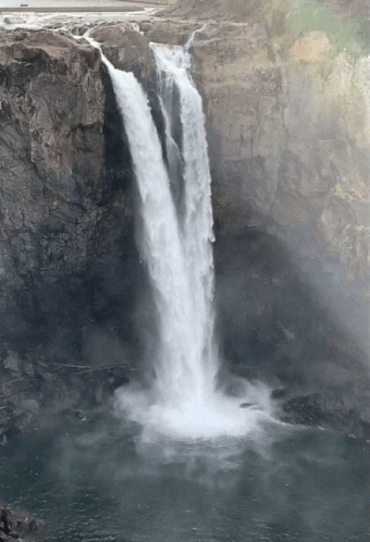 the waterfall has fog over it and sprays the water