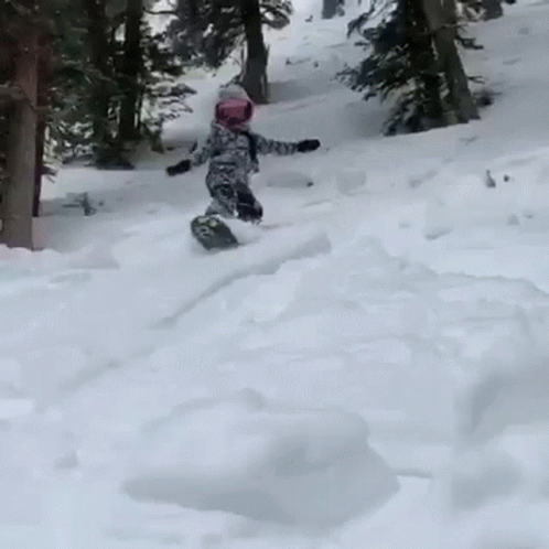 a little boy is sliding down a hill on his snowboard