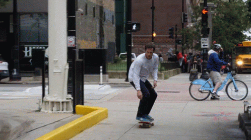 two men skateboarding and riding bikes down a city sidewalk
