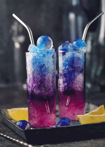 two glasses of purple drinks with oranges in them