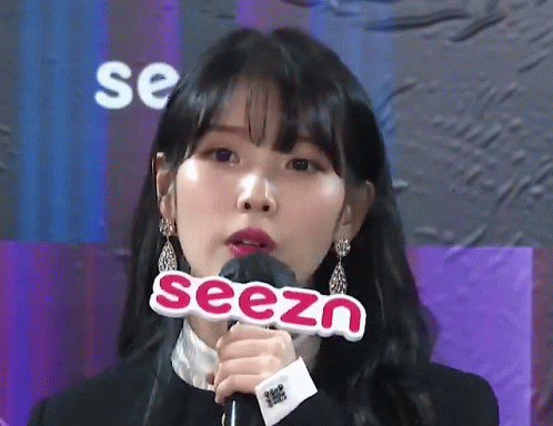 an asian woman holds a microphone and says seezn