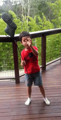 a  holding a stick while standing on a deck