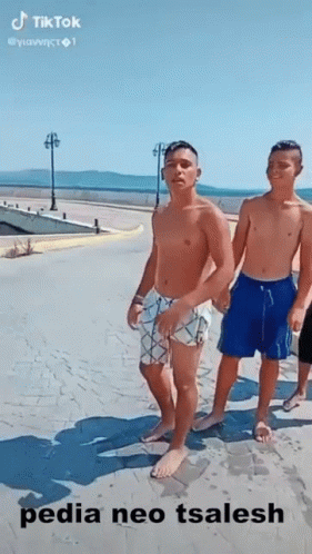a group of three boys walking down a sandy beach