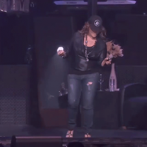 a woman is on stage wearing leather pants and a hat