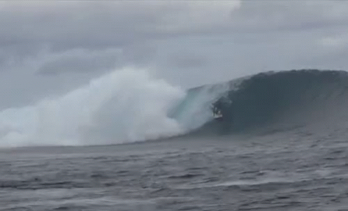 a man surfing on top of a huge wave