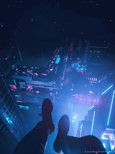 two people standing in front of an illuminated city
