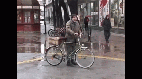 a man with a bicycle holding an empty cart
