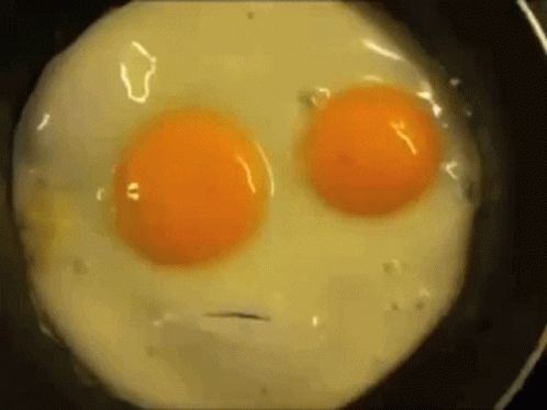 a fried egg in a frying pan with two blue eggs in it