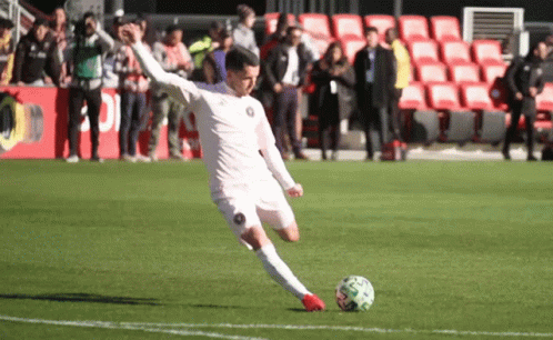 a soccer player in white kicking a ball
