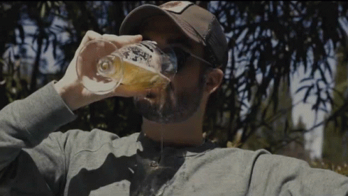a man in a baseball cap and glasses is drinking from a bottle