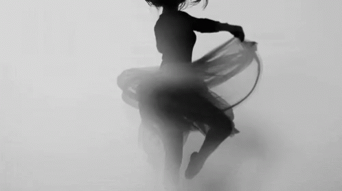a woman dancing in the fog with a round stick