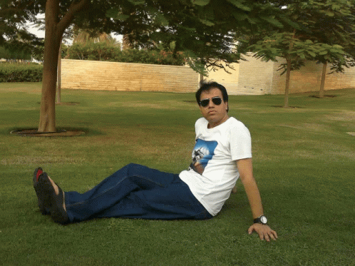 a young man wearing sunglasses lying on the grass