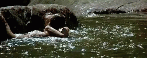 a woman is floating in a river with rocks