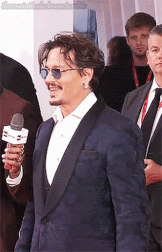 a man in a suit and sunglasses talking on a microphone
