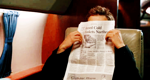 a person reading a newspaper and holding up a newspaper