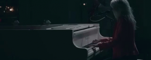a woman playing the piano at night while singing
