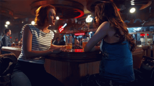 two women are standing at the bar talking