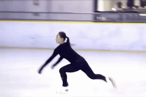 a man in a black outfit skating on a rink