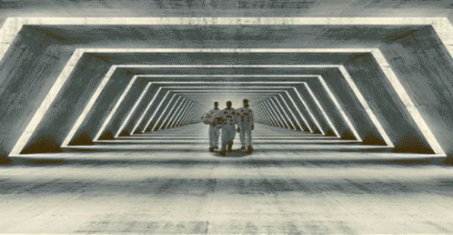 three men standing in a tunnel with many columns