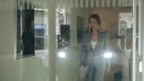 a woman in a suit is looking through a window