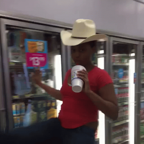 a person wearing a hat holding up a bottle of soda