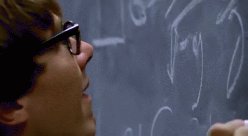 a person writing on a blackboard with glasses